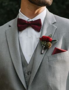 a man wearing a gray suit and red bow tie with flowers in his lapel