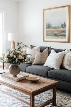 a living room filled with furniture and flowers on top of a coffee table in front of a window