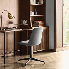 a chair sitting in front of a desk with bookshelf and lamp on it