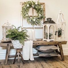 a wooden table topped with lots of plants next to a wall mounted lantern and potted plant