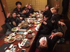 a group of people sitting at a table with plates and bowls of food in front of them