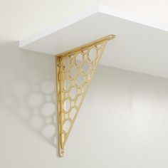 a white wall with a gold shelf on it