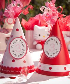 two hello kitty party hats sitting on top of a table next to other decorations and flowers