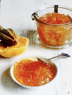 two bowls filled with food sitting on top of a white wooden table next to a spoon