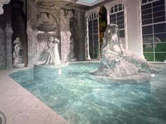 an indoor swimming pool with statues on the wall