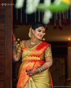 a woman in a yellow and red sari is standing by the door with her hand on her hip