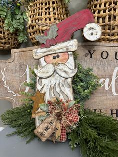 a wooden sign with a santa clause on it's face and christmas decorations around it