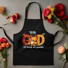 a black apron with the words god all things are possible on it next to flowers