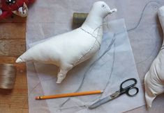 two stuffed animals sitting on top of a table next to scissors and sewing threads