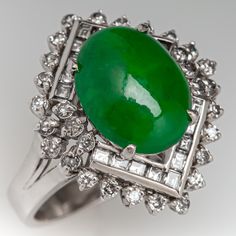 This lovely vintage ring is centered with one (1) oval cabochon cut natural jadeite jade set into a four-prong setting. The jade is bordered with eighteen (18), channel set, baguette cut diamonds and thirty (30), prong set, round brilliant cut diamonds. The ring measures 19.0mm at the top, rises 9.7mm above the finger, tapering to 2.8mm wide and 1.1mm thick at the base of the shank. This ring is currently a size 4.5. Formal Oval Jade Emerald Ring, Formal Art Deco Oval Emerald Ring, Art Deco Jade Jewelry For Formal Occasions, Fine Jewelry White Gold Jade Ring, Luxury White Gold Jade Rings, Formal Art Deco Jade Jewelry, Elegant Emerald Jade Ring With Cabochon, Luxury Silver Jade Round Ring, Luxury Green Jade Rings