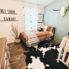 a bedroom with cow skin rugs on the floor, and walls painted in black and white