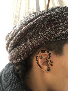 a person with some kind of ear tattoo on their left side of the ear, wearing a hat