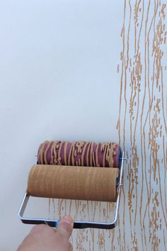 a person is painting a wall with brown and white paint on it, while holding a roller