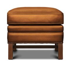 a brown leather ottoman with studding on the legs and foot rests against a white background