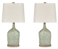 two green vases with white lamps on them are sitting side by side in front of each other