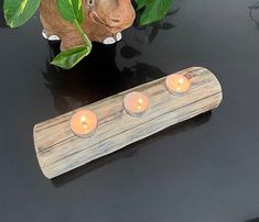 three candles sitting on top of a table next to a small wooden object with leaves