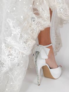 a close up of a person wearing high heel shoes and white dress with sequins