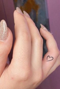 a woman's hand with a heart tattoo on it