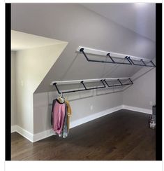 an empty room with some clothes hanging on the wall and a coat rack in the corner