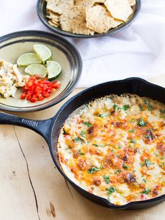 two skillets filled with food sitting on top of a wooden table next to each other