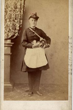 an old photo of a man in uniform holding a baguette and standing next to a table