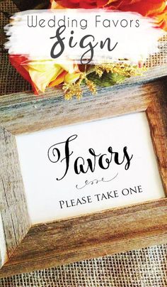 the wedding favors sign is displayed in a wooden frame with flowers and feathers on it