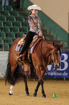 a woman riding on the back of a brown horse in an arena at a rodeo