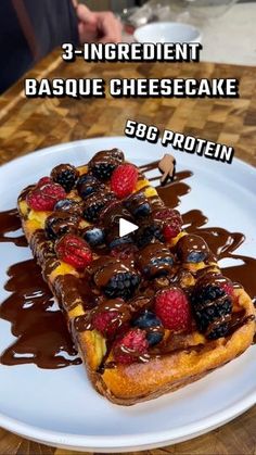 a piece of bread with chocolate sauce and berries on top is sitting on a white plate