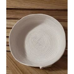 a white bowl sitting on top of a wooden table next to a piece of wood