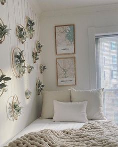 a bed with white sheets and pillows in a bedroom next to a window filled with plants