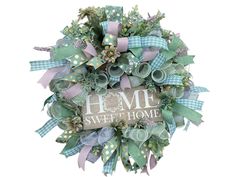 a wreath that has some green and purple ribbons around it with the words home sweet home on it