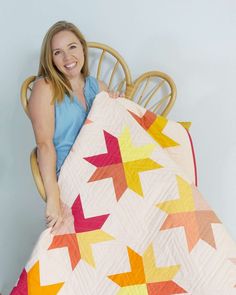 a woman sitting in a chair holding up a quilt