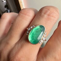 Holy Moly this is a RING. A stunning rosecut Zambian Emerald is set in buttery 14k yellow gold. Accented with over 1/4th of a ct of Brilliant white diamonds and Emily's seagrass band this is truly a ring that will be forgotten. Approx stone size: 18mm x 11mm Approx ct weight: 4.7cts Approx diamond ct: .26cts Mohs hardness: 8 This one of a kind piece is handmade with love in Emily's Hudson Valley studio. It is currently in stock and ready to size and ship. If you have questions about sizing, ship Oval Green Rose Cut Diamond Rings, Oval Emerald Ring With Single Cut Diamonds, Heirloom Oval Emerald Ring With Rose Cut Diamonds, Unique Oval Emerald Ring In Yellow Gold, Unique Yellow Gold Oval Emerald Ring, Yellow Gold Emerald Ring With Rose Cut Diamonds, Oval Emerald Ring With Rose Cut Diamonds, Oval Rose Cut Diamond Rings For May Birthstone, Heirloom Oval Emerald Ring With Single Cut Diamonds