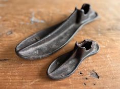 two pieces of metal sitting on top of a wooden table next to each other with holes in them