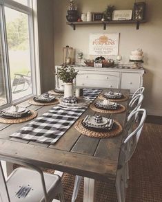 a dining room table with place settings and plates on it, in front of a window