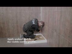 a man is kneeling down in the corner of a shower