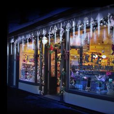 a store front with christmas lights on the windows and decorations hanging from it's windows