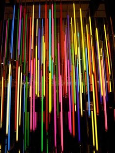 an art installation with multicolored sticks hanging from the ceiling