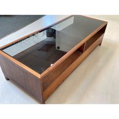 a coffee table with glass top and wooden frame on the bottom shelf, in an empty room