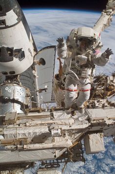 an astronaut floating in the air next to a large space shuttle with another person on it