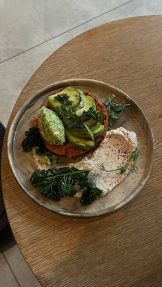 a wooden table with a plate of food on it, including bread and spinach