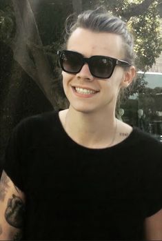 a woman in black shirt and sunglasses smiling