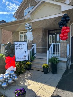 a welcome to the jungle sign in front of a house with balloons and streamers