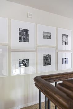 A white frame gallery wall with black and white photos. Wall Picture Frame Ideas Living Room, Assorted Mirrors On Wall, Top Of Stairway Wall Decor, Frame Pictures On Wall, End Of Hall Gallery Wall, White Frame Photo Wall, Large Gallery Wall Hallway, Corner Gallery Wall With Chair, Dining Room Gallery Wall Ideas Modern