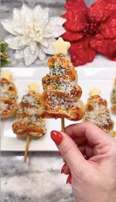 a person holding up some food on a stick with christmas decorations in the back ground