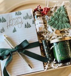 an open gift box with christmas items and writing paper on the table next to it