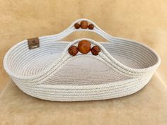 a white rope basket with wooden beads on the handles and sides, sitting on a tan surface