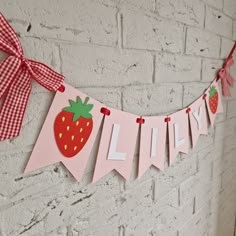 a pink banner with strawberries hanging from it's sides on a brick wall