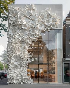 a large white sculpture on the side of a building with lots of flowers growing out of it