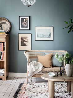 a living room with blue walls and pictures on the wall, including a wicker couch